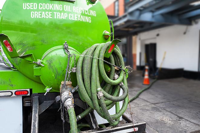 a professional plumber using a pump to empty a grease trap in Cold Springs
